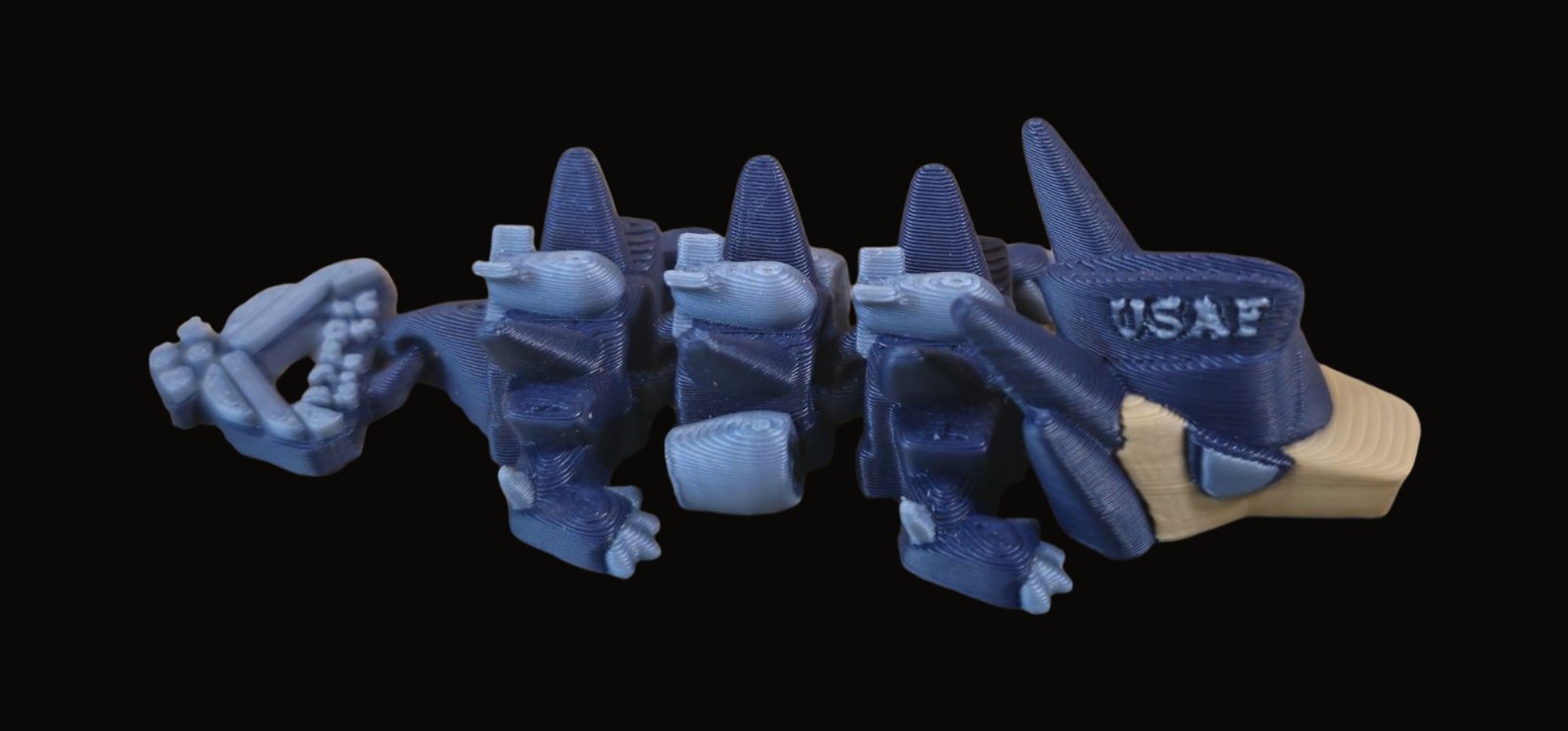 Blue articulated Air Force dragon with a USAF cap, little jets along its back and wings on the tail