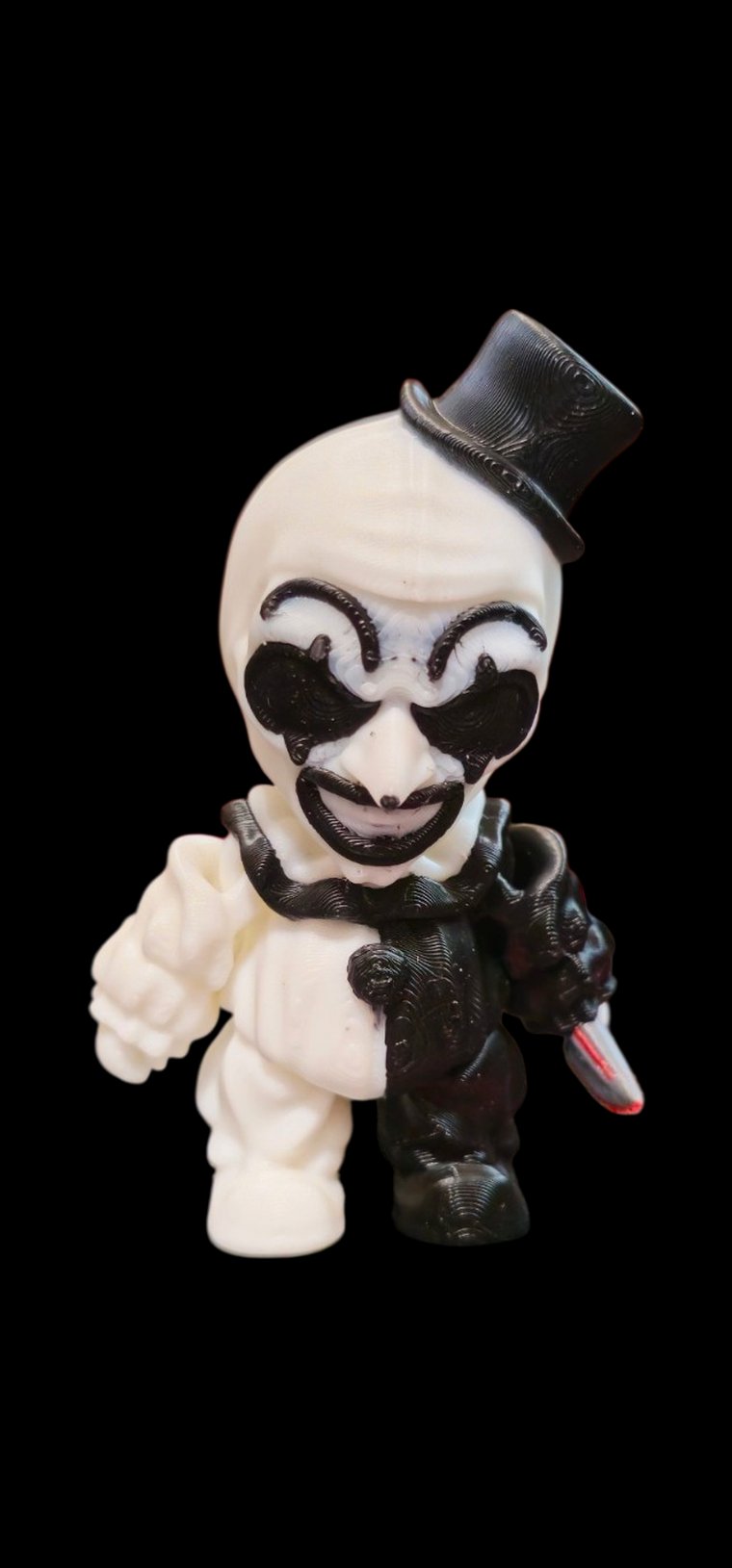Mini black-and-white clown figure with a tiny top hat and a bloody knife