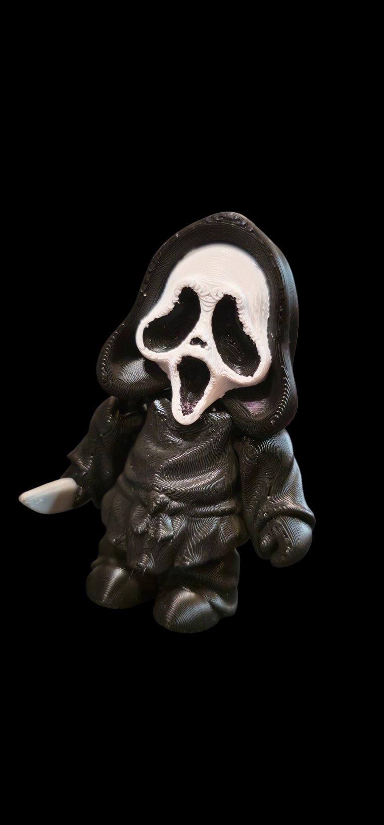 Small black-robed figure with a white ghost mask and a knife