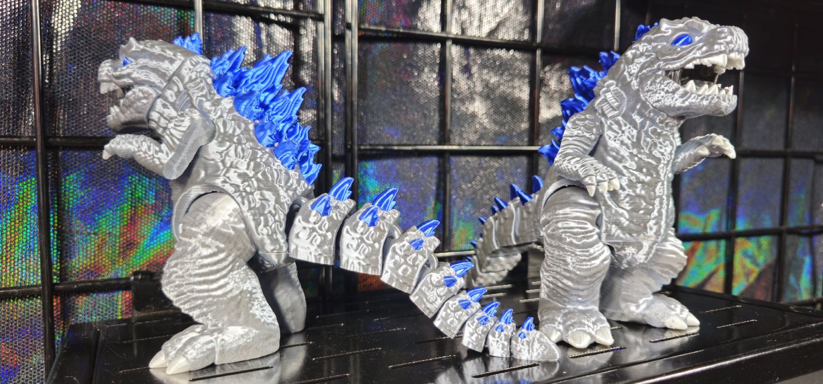 Two silver and blue articulated Godzilla prints with segmented tails