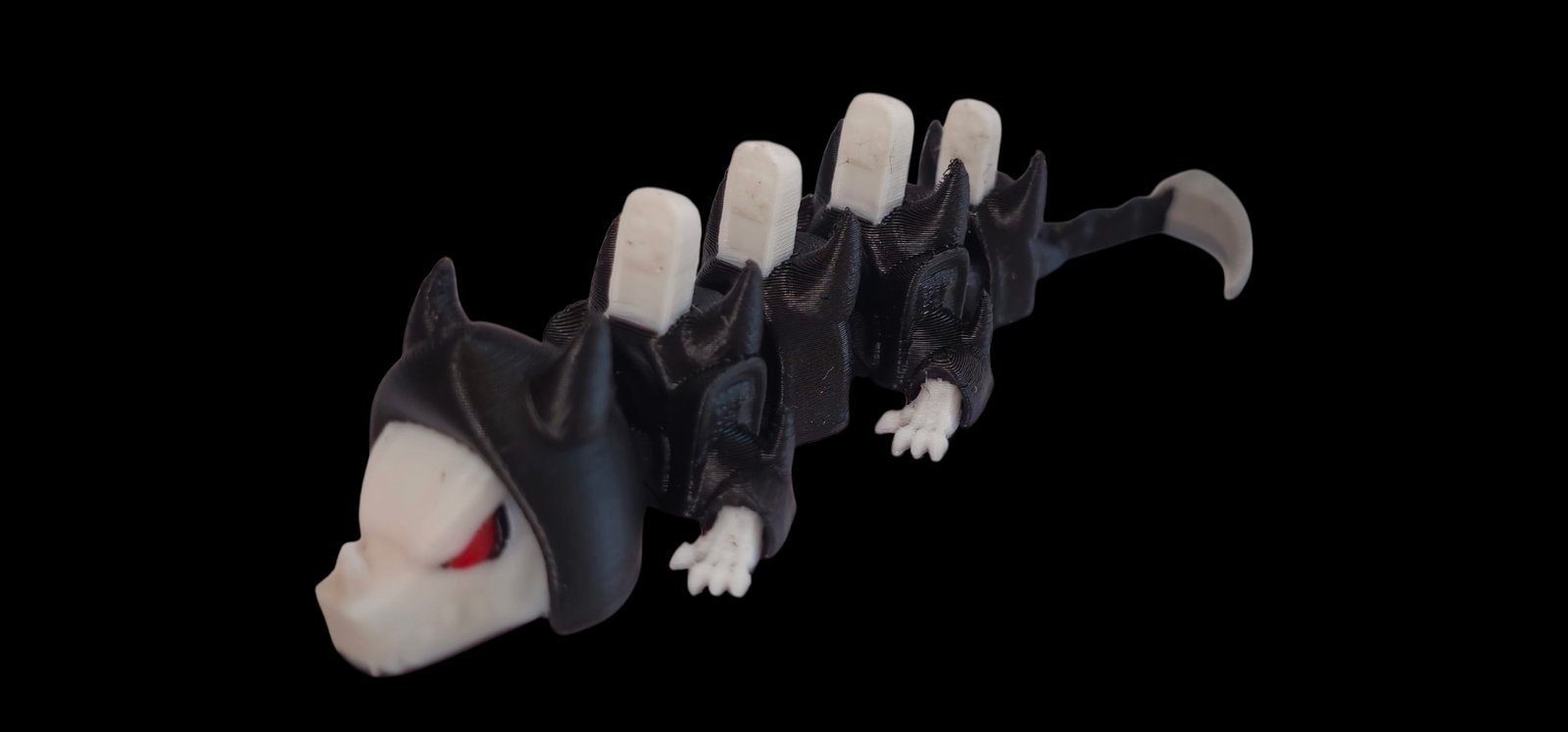 Black articulated Grim Reaper dragon with red eyes, a skull face and white tombstone spines