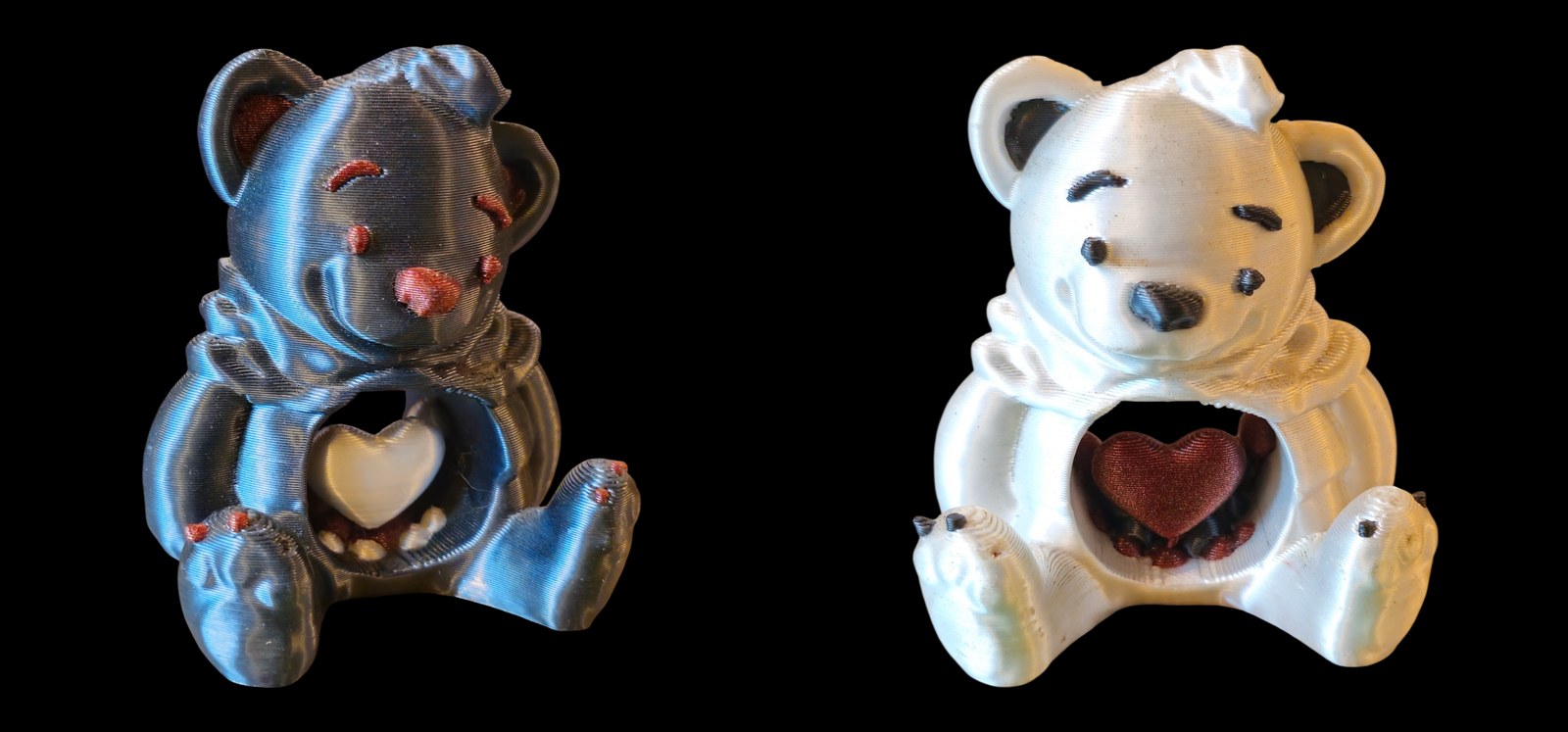 Two seated heart bears, one silky black with red details and one white with black details, each holding a heart in its belly