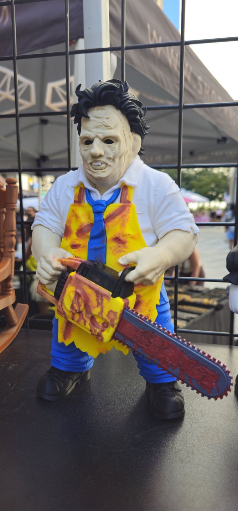 Hand-painted chainsaw-wielding figure in a yellow apron and blue tie