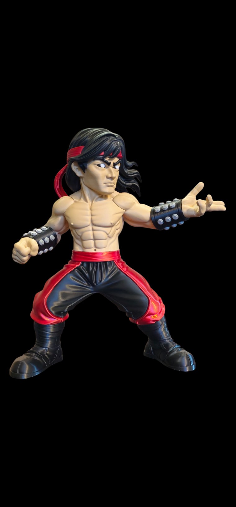 Liu Kang from Mortal Kombat figure in a fighting stance with long black hair, red headband, studded wristbands and red and black pants