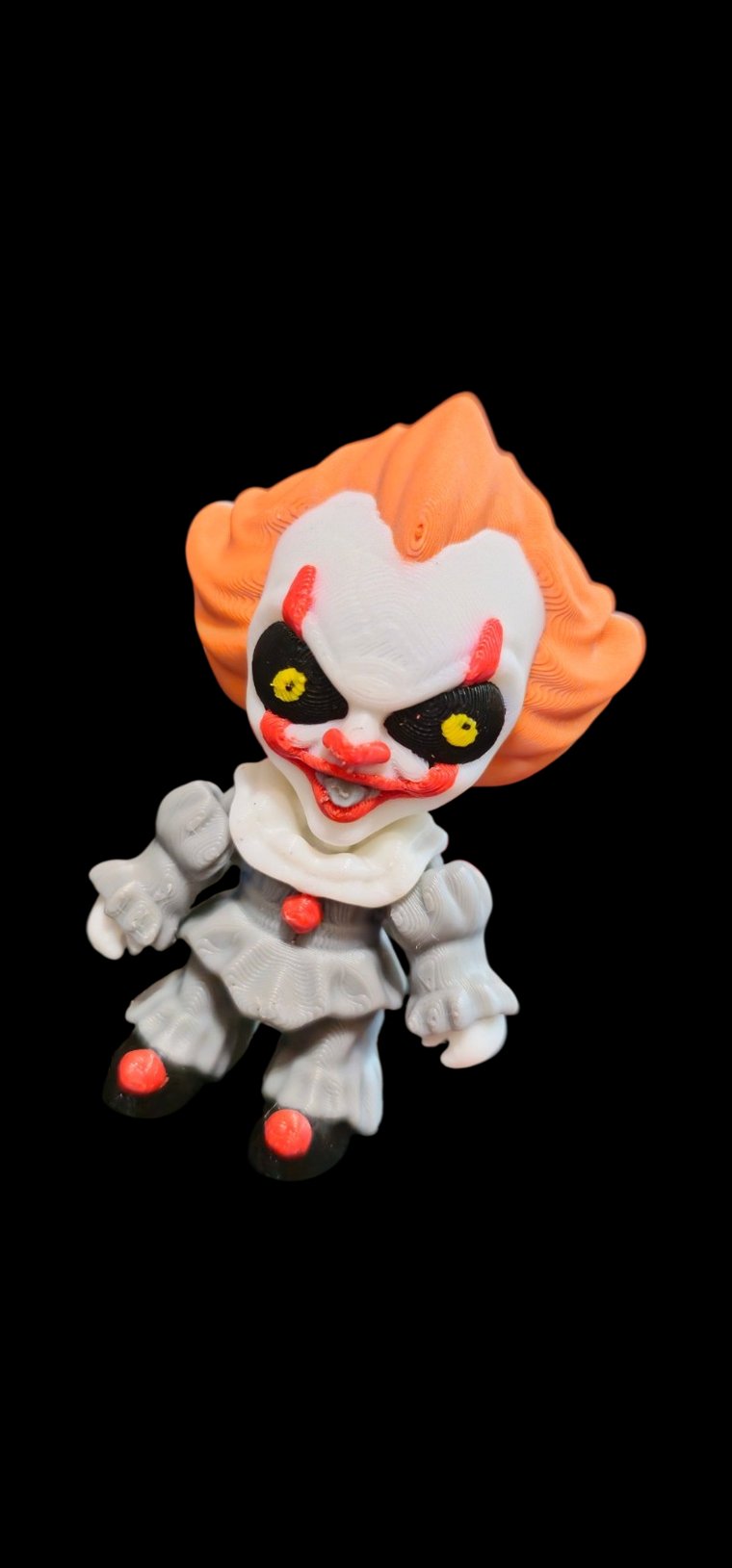 Mini Pennywise clown figure with orange hair, yellow eyes, red nose and a grey ruffled suit