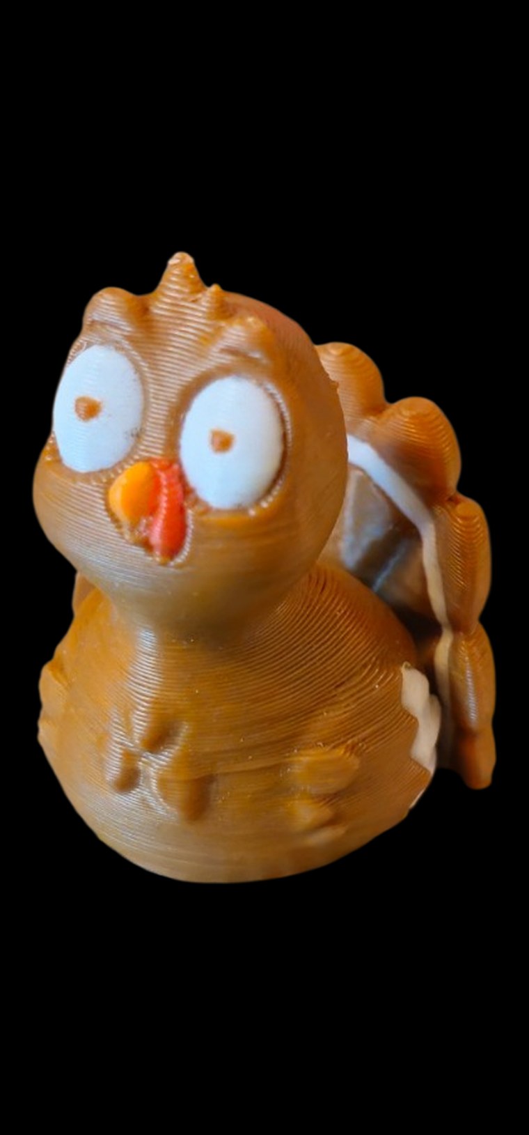 Brown turkey figure with big white eyes, an orange beak and tail feathers
